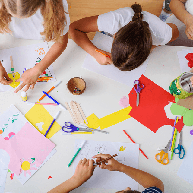 Lapset piirtävät ja askartelevat yhdessä lattialla