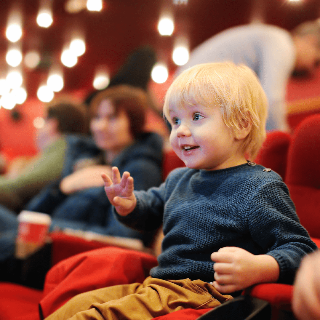 Little boy watching a theatre performance in the audience – wide-eyed cultural discovery