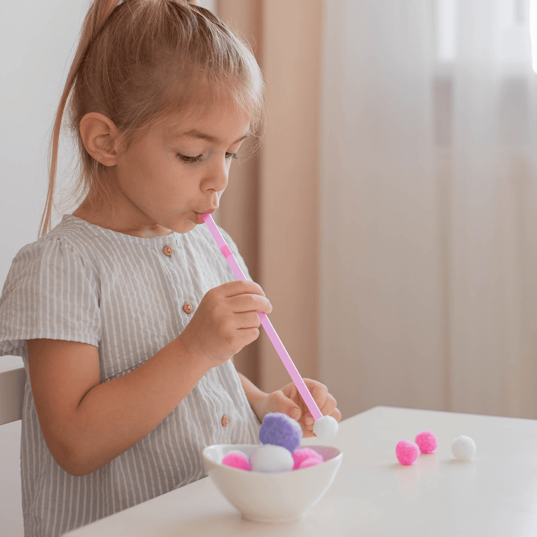 Girl blowing a ball with a straw – fun party games for kids with minimal materials and maximum giggles.