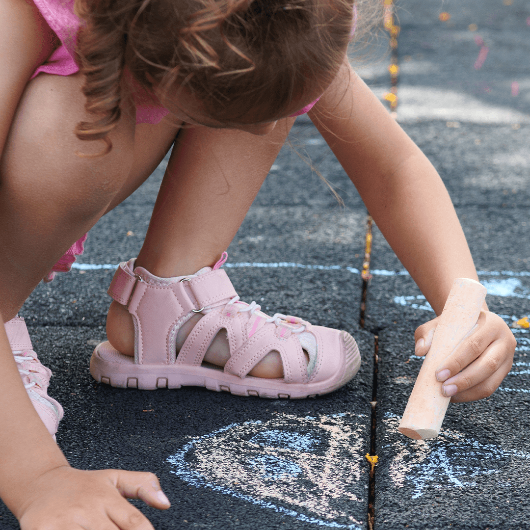  Tyttö piirtää asfalttiin katuliiduilla – luovaa tekemistä lapsille ulkona.