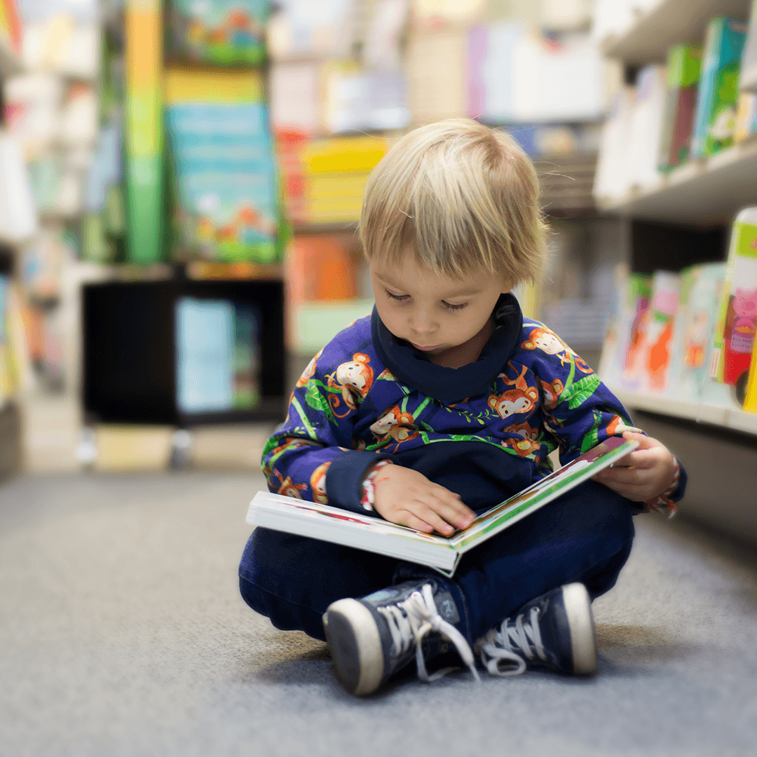Little boy reading a book on the library floor – cozy and focused storytime