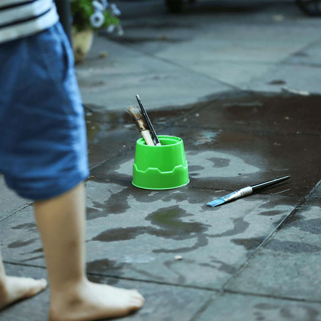 Lapsi maalaa asfalttiin vedellä – luovaa kesäohjelmaa lapsille pihalla 