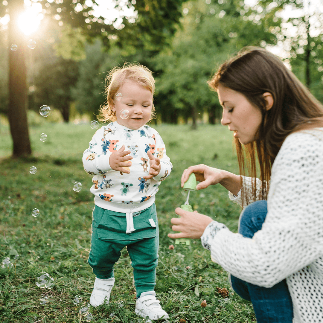 Mother and young child blowing soap bubbles in the park – playful bonding outdoors