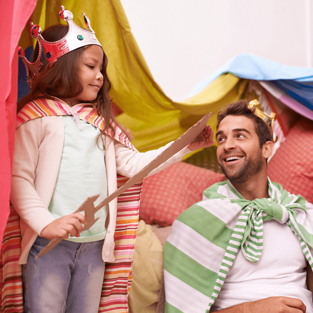 Isä ja tytär esittävät kotiteatteria olohuoneessa – hauskaa tekemistä lapsille sisällä.