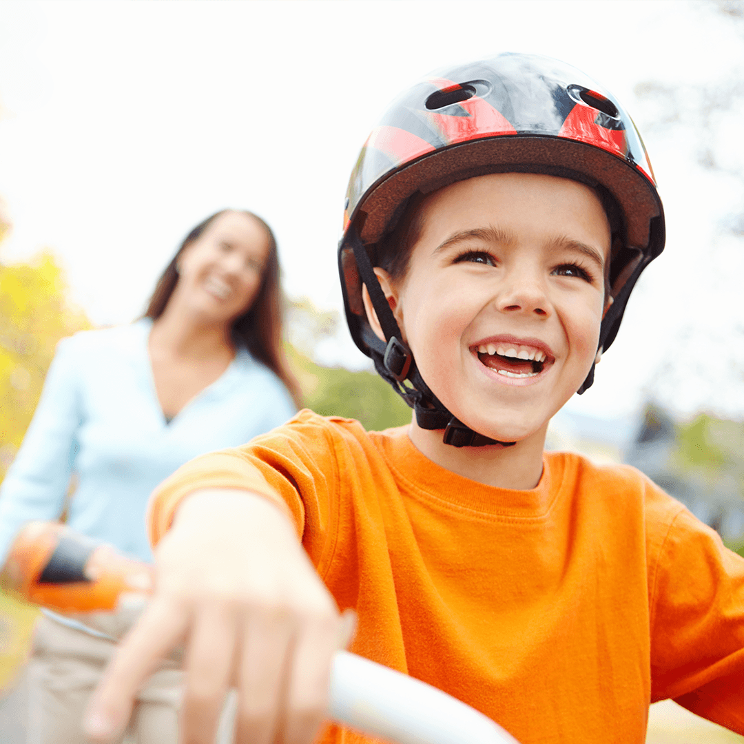 Poika ja äiti pyöräilemässä ulkona – lasten liikuntaa perheen kanssa luonnossa