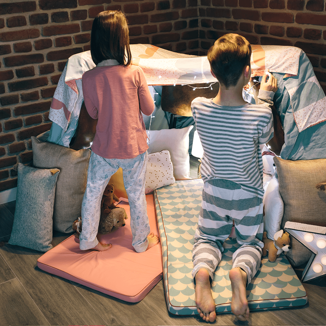 Kids building a blanket fort with couch cushions – creative indoor activities for a rainy day.