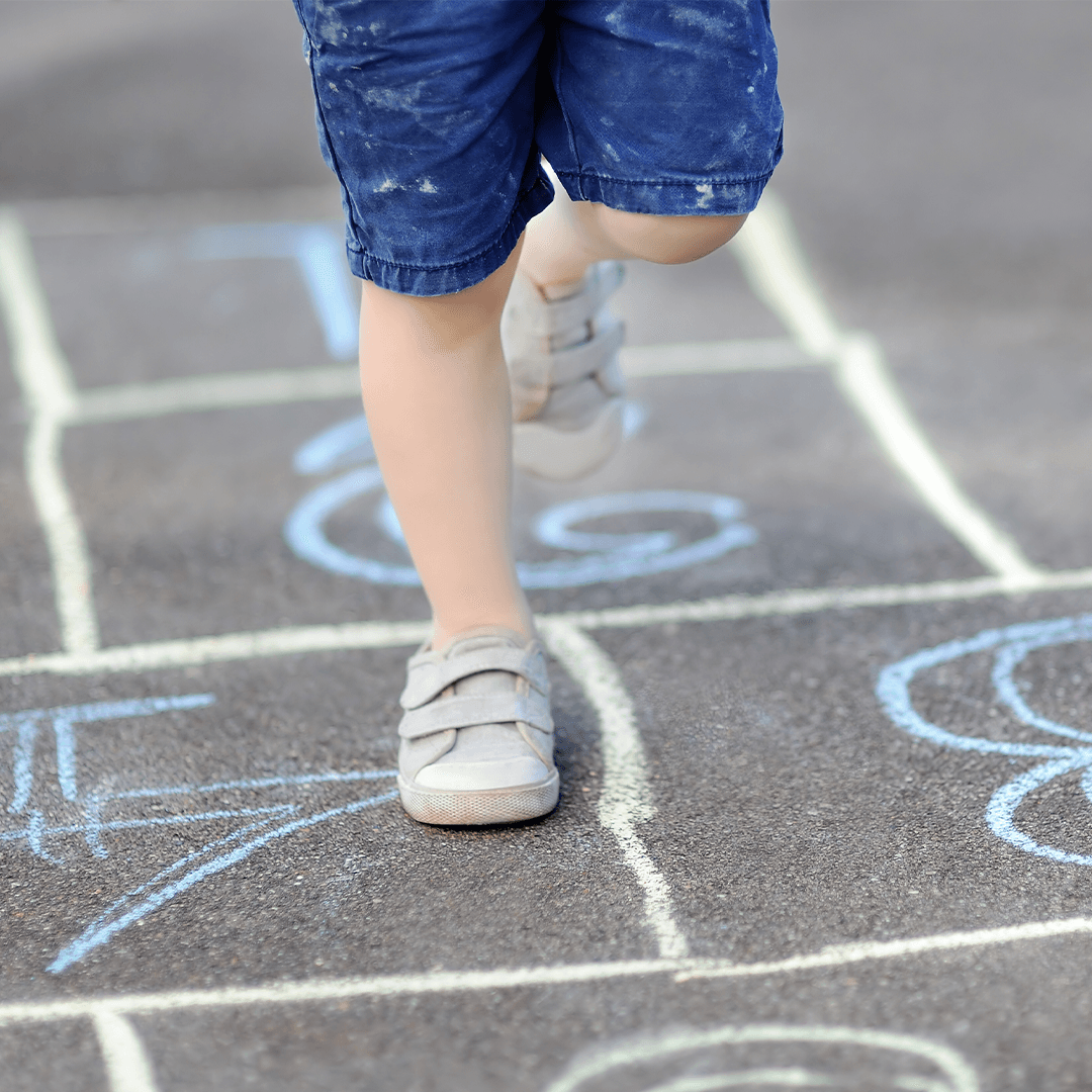 Tyttö leikkii hyppyruudukolla – hauskaa ja kehittävää lasten liikuntaa