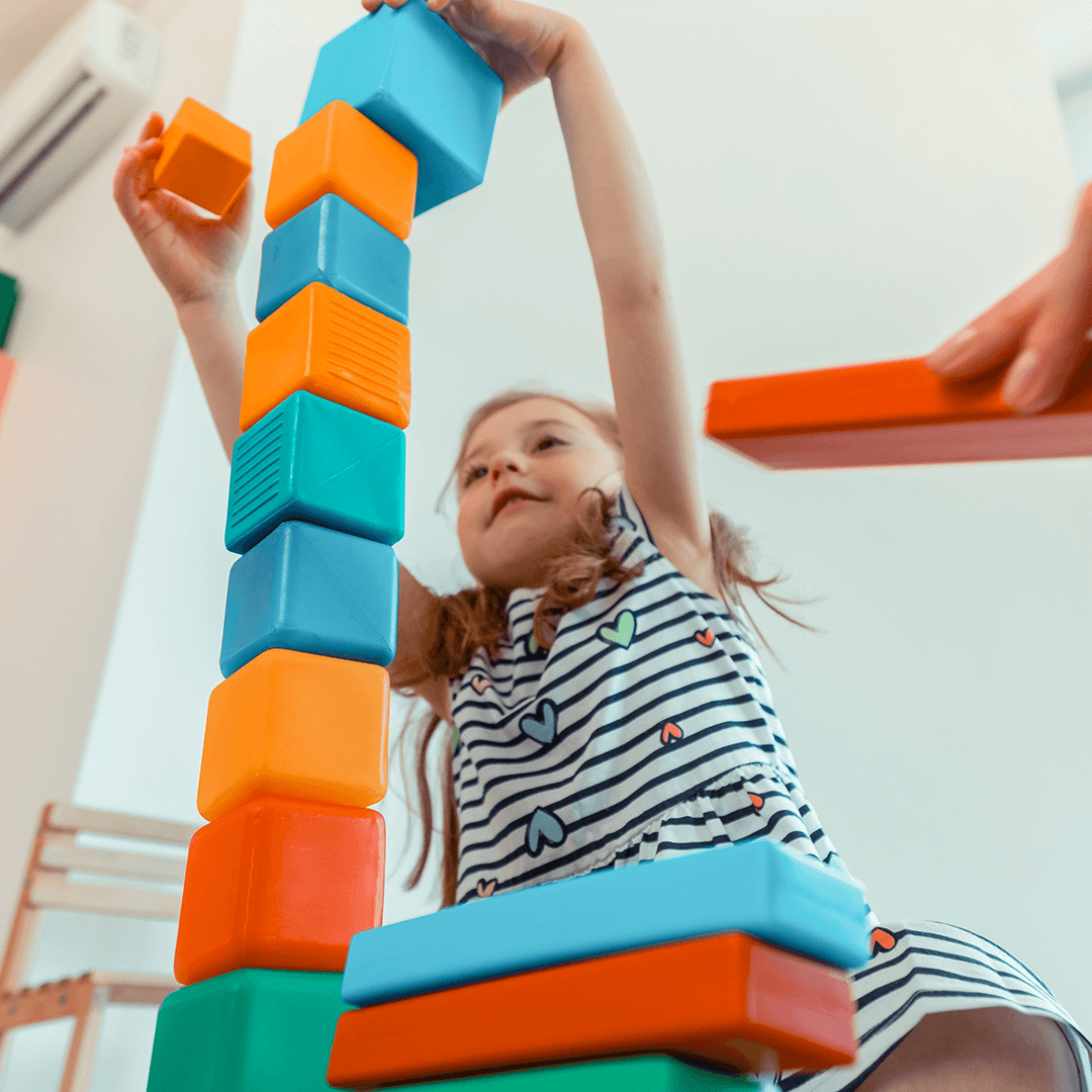 Child stacking blocks, developing motor skills through movement for kids