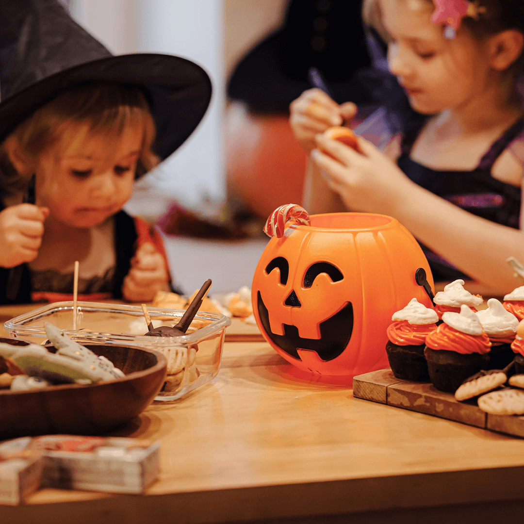 Lapset koristelevat halloween-leivonnaisia yhdessä